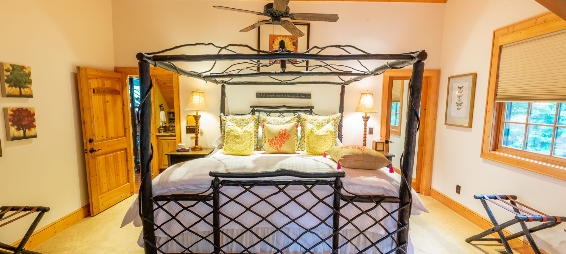 View of River Watch Bedroom... Twig Headboard and Footboard With canopy made of twigs. Pillows on bed... Luggage racks on each side wall. Fan over bed and pictures on walls